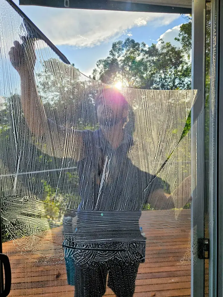 Soapy window being cleaned, with the technician visible through the glass