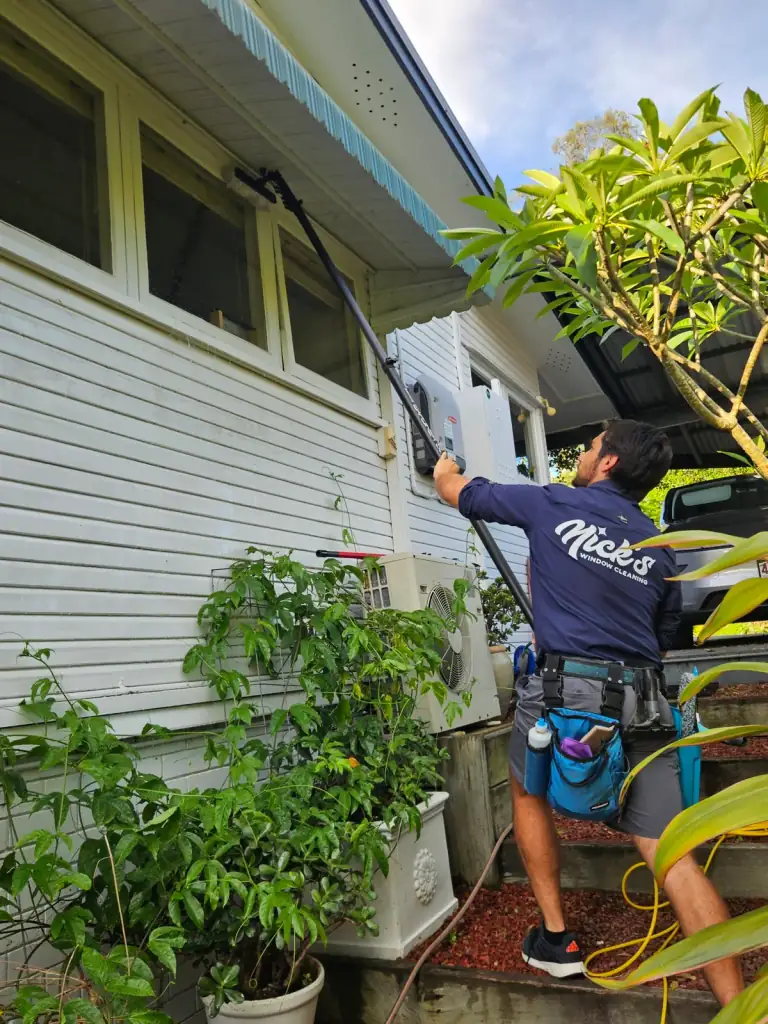 Technician cleaning the exterior windows of a Brisbane home with an extension pole