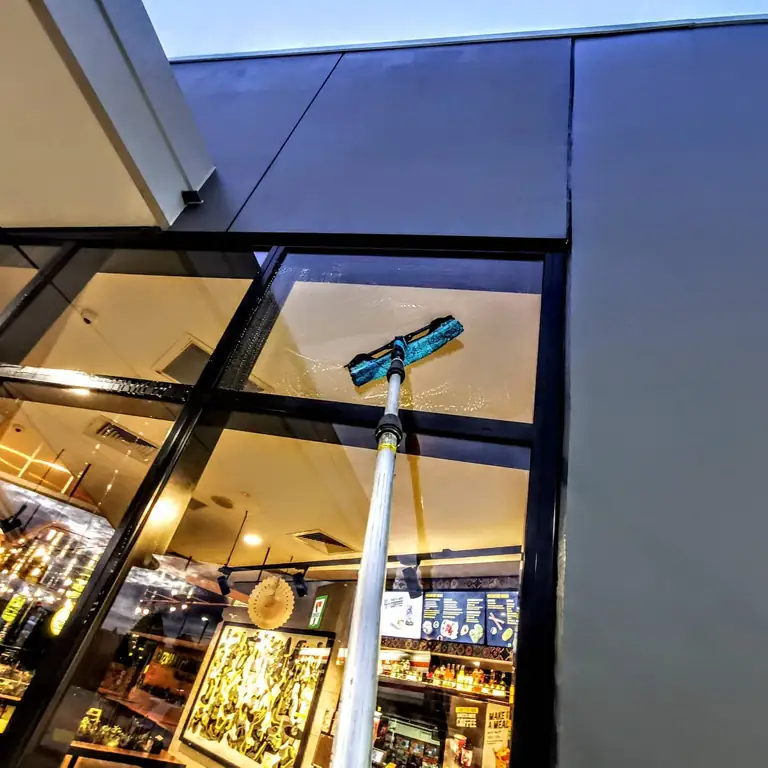 Cleaning a restaurant's upper windows with an extension pole