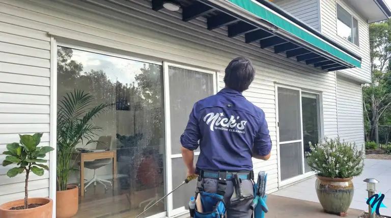 Technician cleaning the sliding glass doors of a Brisbane home